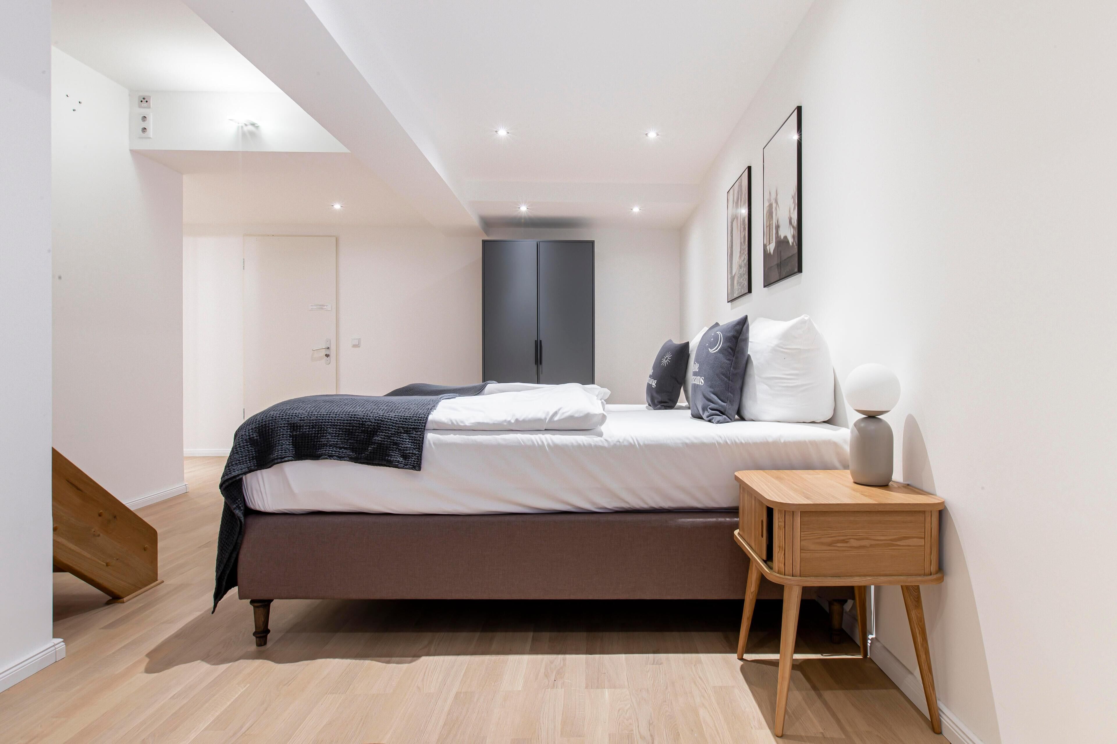 Ein modernes Schlafzimmer mit Bett, Nachttisch und Kleiderschrank.