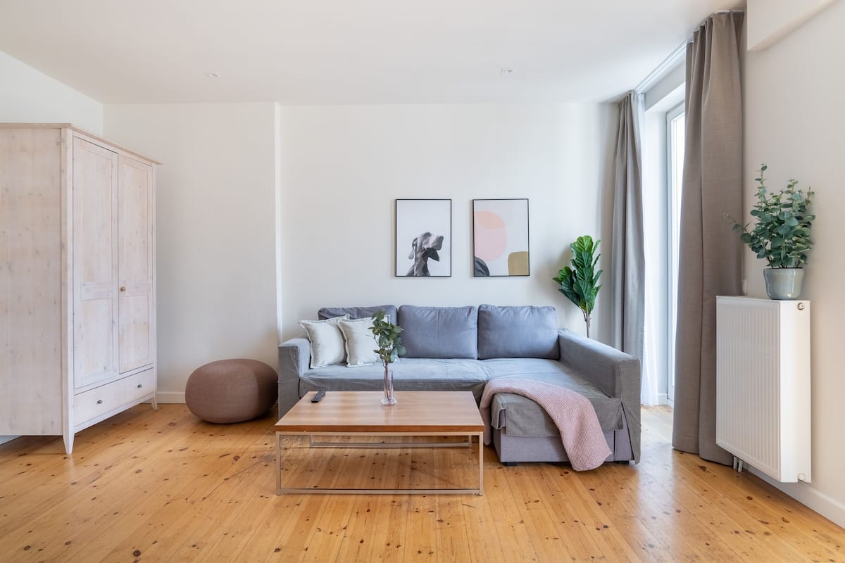 Un salon moderne avec un plancher en bois, un canapé gris et une table basse en bois.