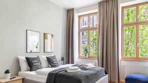 Ein Schlafzimmer mit einem Bett, einem Nachttisch und einem Fenster mit Vorhängen.