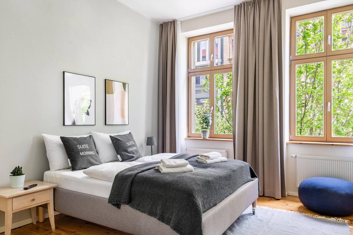 Une chambre à coucher avec un lit, une table de chevet et une fenêtre avec des rideaux.