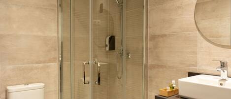 A modern bathroom with a glass-enclosed shower, a white toilet, and a sink with a wooden tray.