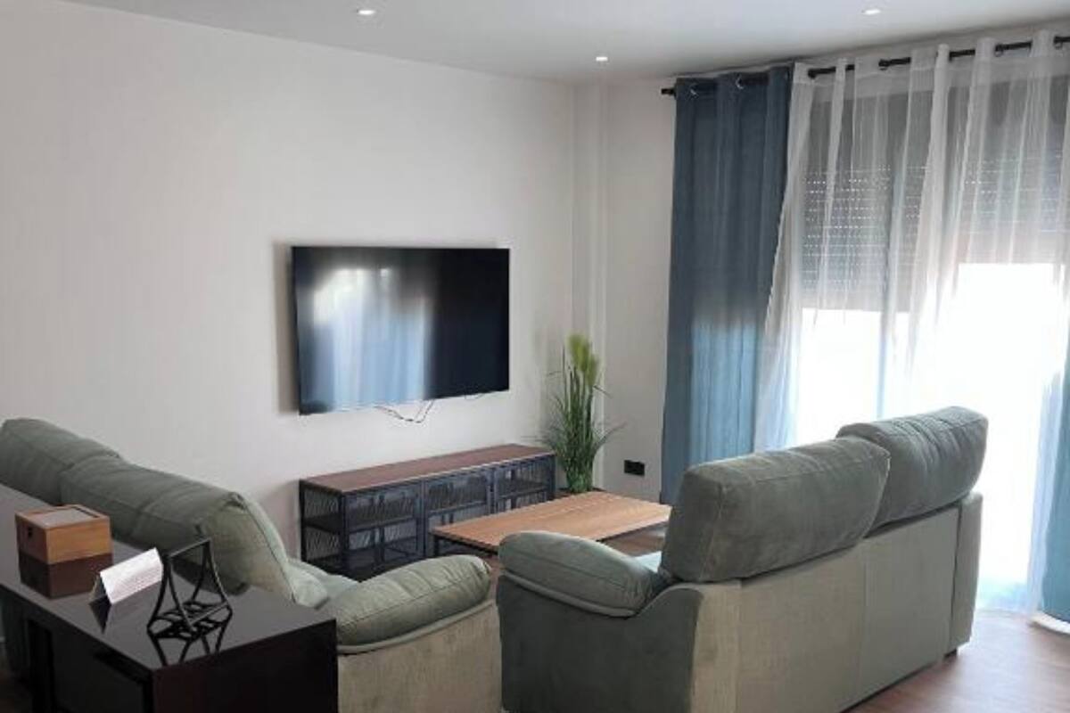 A modern living room with a sofa, a coffee table, and a TV mounted on the wall.