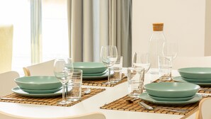 A dining table set with green plates, clear glasses, and a bottle. - Apartamentos Kouohana (Fuengirola)