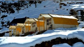 Una hilera de cabañas con techo nevado y cielo despejado.