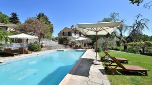 A swimming pool with lounge chairs and umbrellas, surrounded by a stone pathway and lush greenery. - Antica Posta, Castellina in Chianti, Siena and Chianti (Castellina in Chianti)