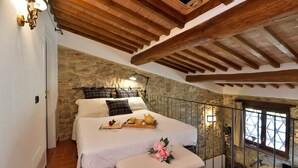 A bedroom with a stone wall, wooden beams, a bed with a tray of tea and a book, and a balcony with a view. - Antica Posta, Castellina in Chianti, Siena and Chianti (Castellina in Chianti)