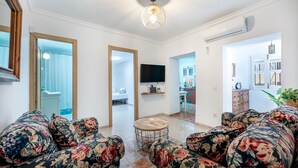 A living room with floral-patterned sofas, a TV, and a ceiling light. - Cozy townhouse in Benalmadena 3min from the beach (Benalmádena)