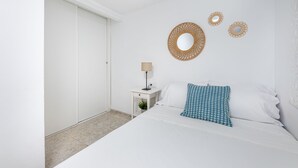 A bedroom with a bed, a nightstand, a lamp, and three wall-mounted mirrors. - Cozy townhouse in Benalmadena 3min from the beach (Benalmádena)