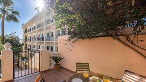 A balcony with a table set for breakfast, a potted plant, and a view of a multi-story building. - Cozy townhouse in Benalmadena 3min from the beach (Benalmádena)