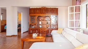 Een woonkamer met een houten kast, een witte bank en een houten salontafel.