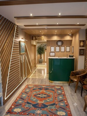 A hotel lobby with a reception desk, a clock, framed certificates, and a patterned rug. - By Kinyas Hotel (Istanbul)