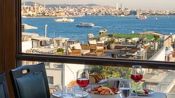 Mesa posta para refeição com vista para paisagem urbana e água.
