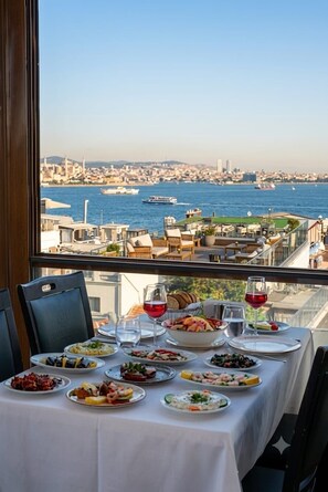 A table set for a meal with a view of a cityscape and water. - By Kinyas Hotel (Istanbul)