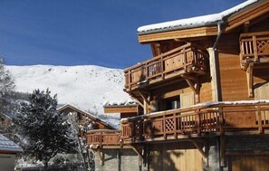 Eine Holzhütte mit Balkon, umgeben von schneebedeckten Bergen.