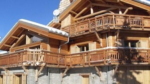 A wooden chalet with multiple balconies and a stone foundation.
