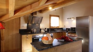 A kitchen with wooden cabinets, a stainless steel refrigerator, and a window providing natural light.