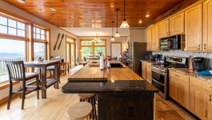 A spacious kitchen with wooden cabinets, a large island, and a view of the outdoors. - Gorgeous Chalet - Incredible Views - Hot Tub - Fire Pit (Snowshoe)