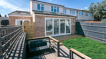 Relax on the spacious deck with seating, surrounded by a well-maintained lawn and a wooden fence.