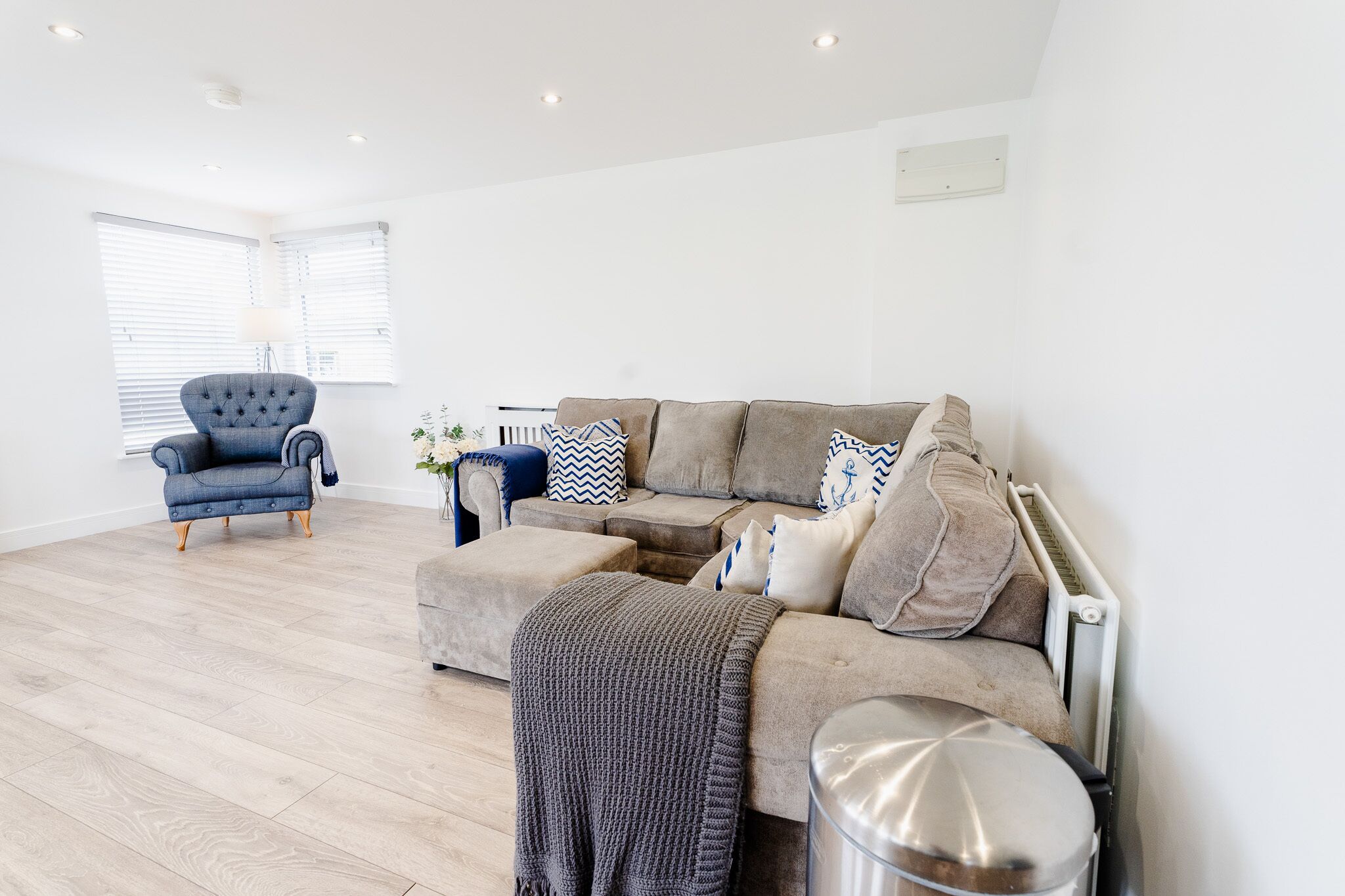 Ein modernes Wohnzimmer mit einem grauen Sofa, einem blauen Sessel und einem kleinen Beistelltisch.