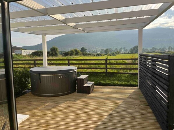 A hot tub under a pergola with a view of a green field and mountains. - Castle View Chalet by Clonlum Cottages (Newry)