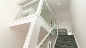 A modern staircase with glass railings and carpeted steps. - King Pin Corner (Stevenage)