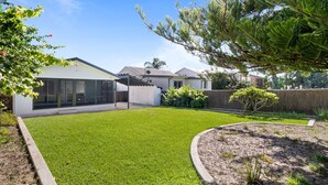 A modern house with a well-maintained lawn, a covered patio, and a fenced backyard.