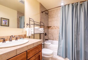 A bathroom with a sink, mirror, towel rack, toilet, and bathtub.