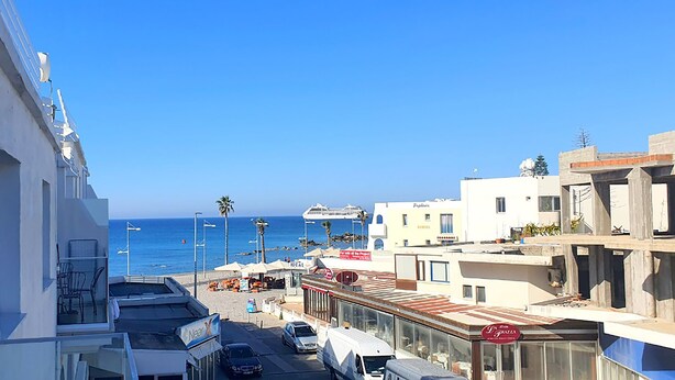 Un hotel costero con vistas al mar, que cuenta con balcones, una zona en la playa y un restaurante.