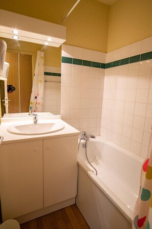 Een badkamer met een wastafel, spiegel en bad.