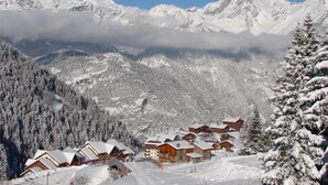 A snow-covered mountain village with wooden chalets and a ski slope.