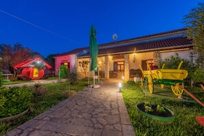 Un camino de piedra que conduce a una casa con techo de tejas y un letrero que dice "KONOA".
