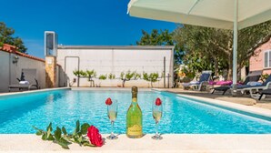 A pool area with a bottle of Câdel Bosco wine, two glasses, and a rose. - Villa Štrkalj (Policnik)