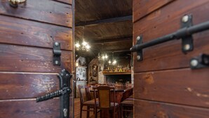 A wooden door with a brass handle and lock, leading into a room with a wooden floor, a table with chairs, and a chandelier. - Villa Štrkalj (Policnik)