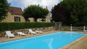 A rectangular swimming pool with clear blue water, surrounded by a concrete deck. There are white lounge chairs aligned along the pool's edge. - Apartment in stone house (Saint-Crépin-et-Carlucet)