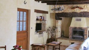 A rustic interior with a stone fireplace, wooden furniture, and a television mounted on the wall. - Apartment in stone house (Saint-Crépin-et-Carlucet)