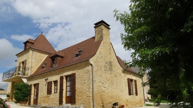 A two-story stone house with a red-tiled roof, a balcony on the upper floor, and a gravel driveway. - Apartment in stone house (Saint-Crépin-et-Carlucet)