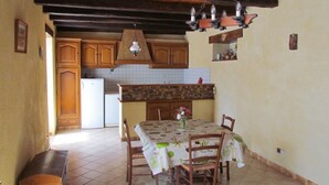 A kitchen with wooden cabinets, a tiled backsplash, and a dining table with chairs. - Apartment in stone house (Saint-Crépin-et-Carlucet)