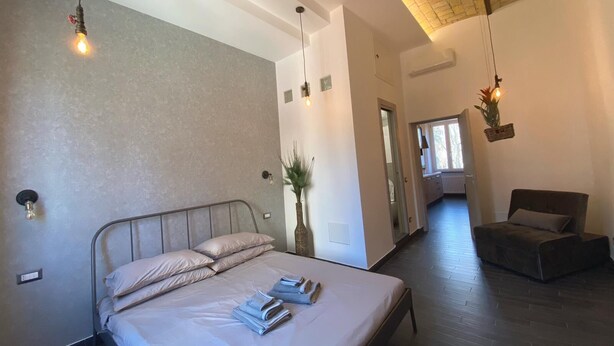 Une chambre moderne avec un grand lit, un petit coin salon et une lucarne.