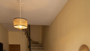 A staircase leading to a second floor, a wooden door, a black console table with a lamp, and a potted plant.