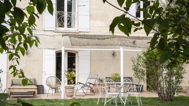 A covered patio with outdoor furniture, a white fence, and a garden.