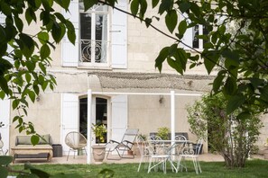 Eine überdachte Terrasse mit Gartenmöbeln, einem weißen Zaun und einem Garten.
