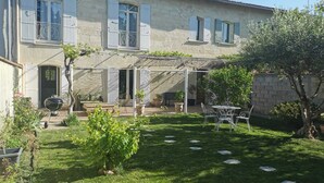 A two-story house with a covered patio, outdoor seating, and a garden.