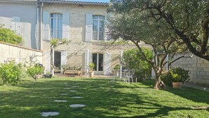 A house with a well-maintained lawn, a patio with outdoor furniture, and a large tree.