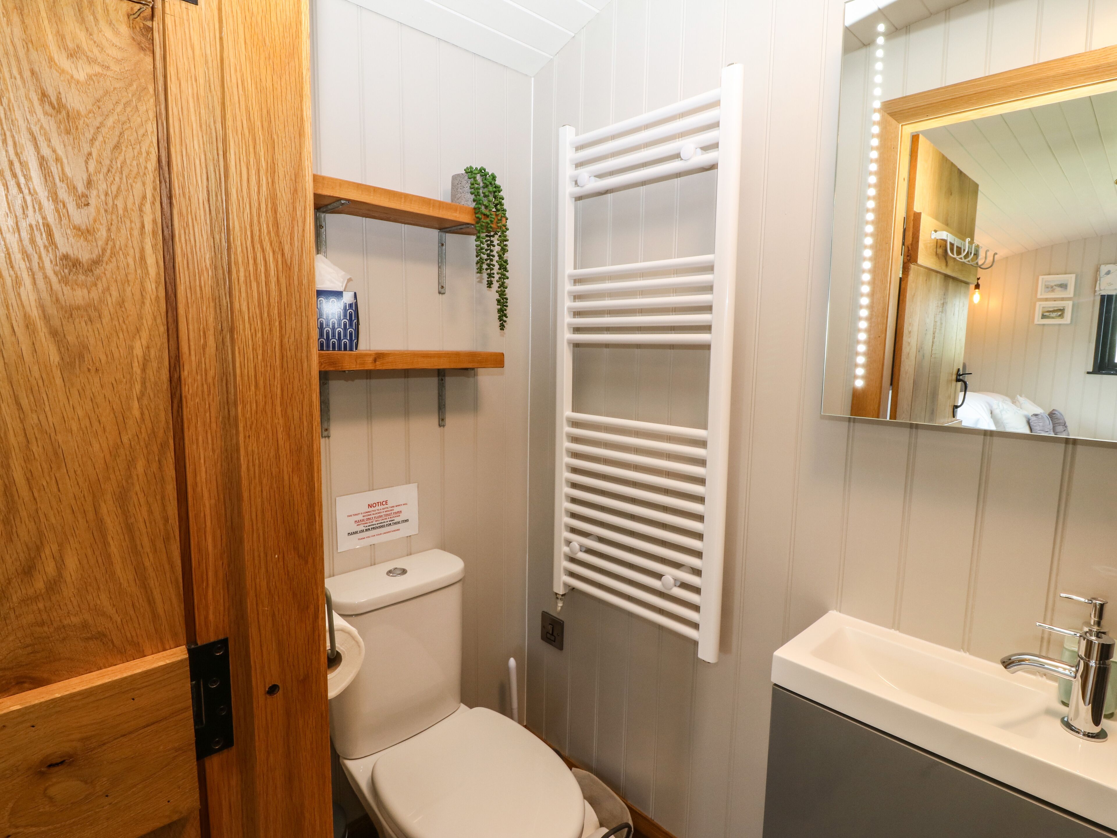 A bathroom with a toilet, a sink, a mirror, and a towel rack.