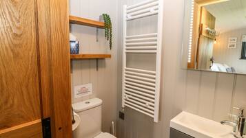 A bathroom with a toilet, a sink, a mirror, and a towel rack.