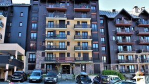 A multi-story hotel with balconies, a stone facade, and a parking area. - 50m from resort center, 2nd floor, swimming pool, balcony, tv, ski locker, 32m², Risoul (Risoul)