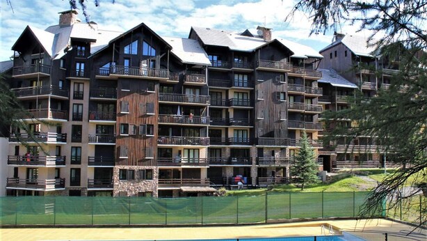A multi-story hotel with balconies, a swimming pool, and a ski slope in the background. - 50m from resort center, 2nd floor, swimming pool, balcony, tv, ski locker, 32m², Risoul (Risoul)
