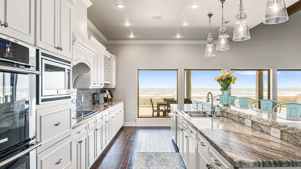 A modern kitchen with white cabinetry, stainless steel appliances, and a large island.