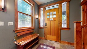 A wooden bench, a door with glass panels, and a window with a view of trees. - Lodestar #2001 5 Bedroom Home by RedAwning (Mammoth Lakes)
