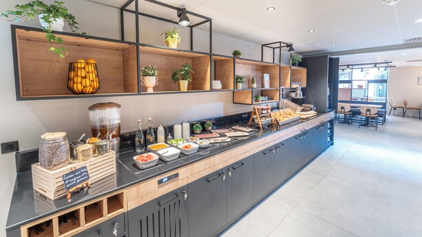 Een moderne keuken met een lange toonbank, diverse etenswaren en planten.